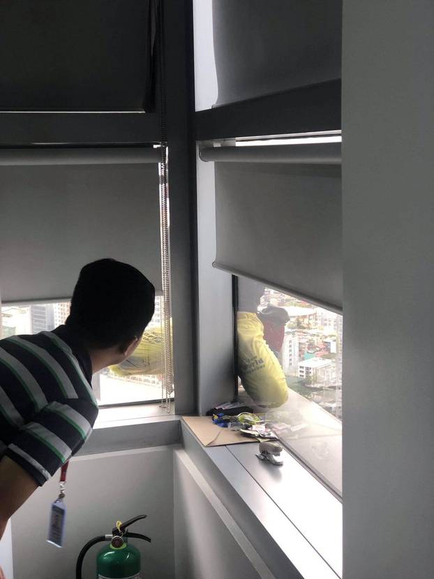 A man looks out a window as Alain Robert, also known as "the French Spider-Man" or "the Human Spider", climbs the GT Tower in Manila