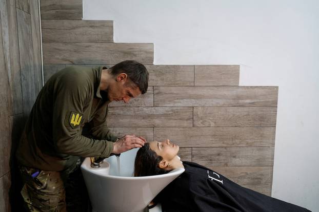 Hairdresser and Ukrainian Territorial Defence unit volunteer works at a beauty salon, in Kyiv