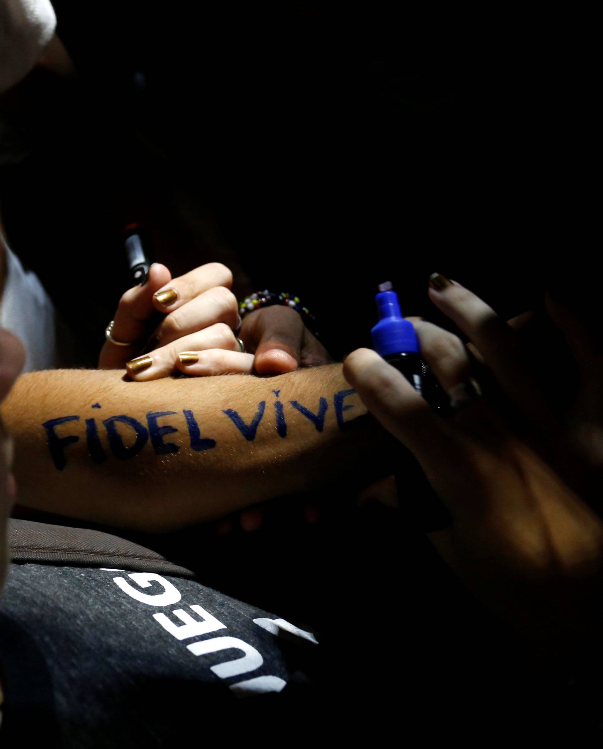 A woman writes "Fidel lives" on her forearm during a massive tribute to Cuba's late President Fidel Castro on Revolution Square in Havana