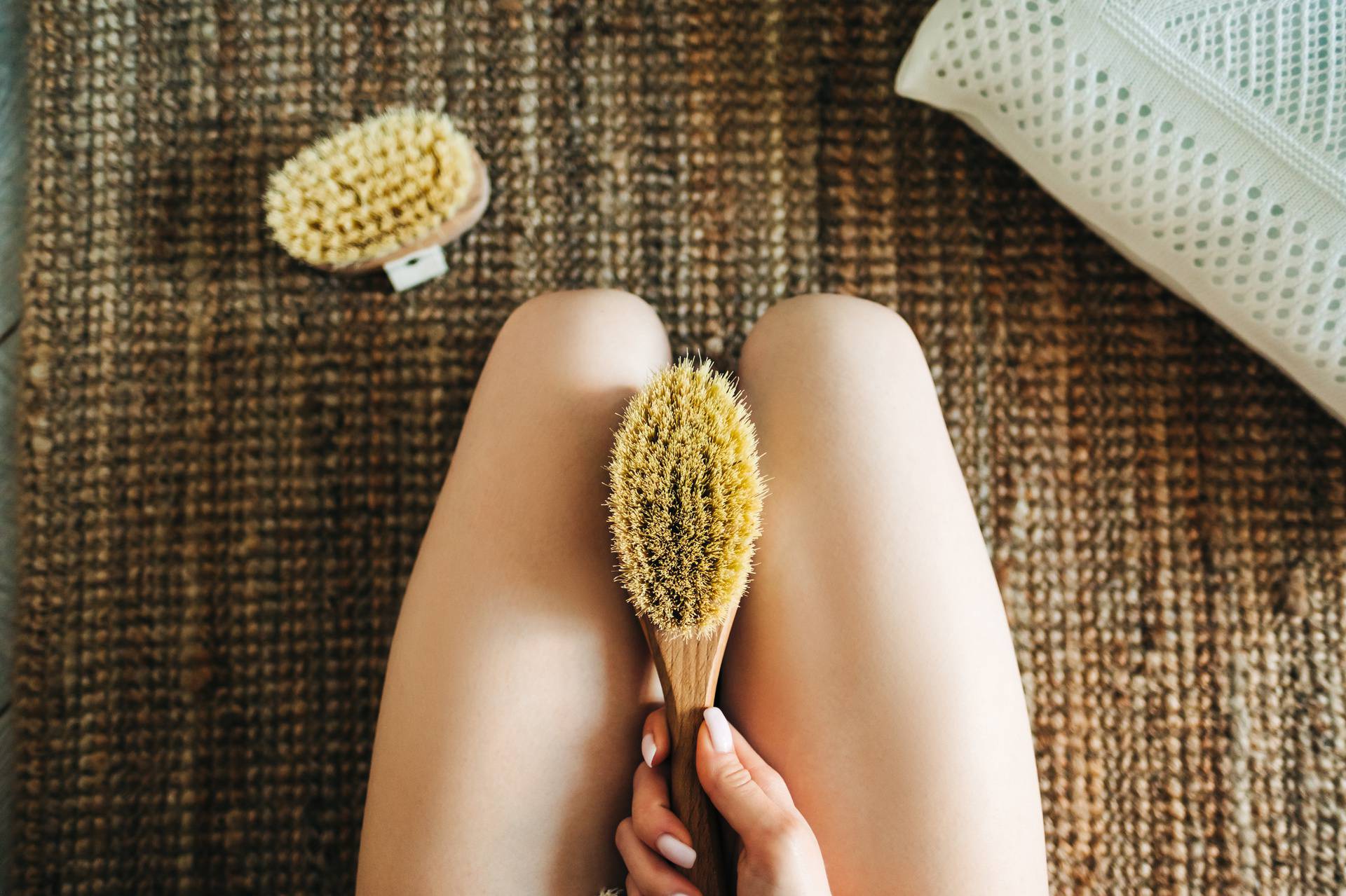 Woman holding wooden brush and doing dry massage on her feet. Self care conceptWoman holding wooden brush and doing dry massage on her feet. Self care concept