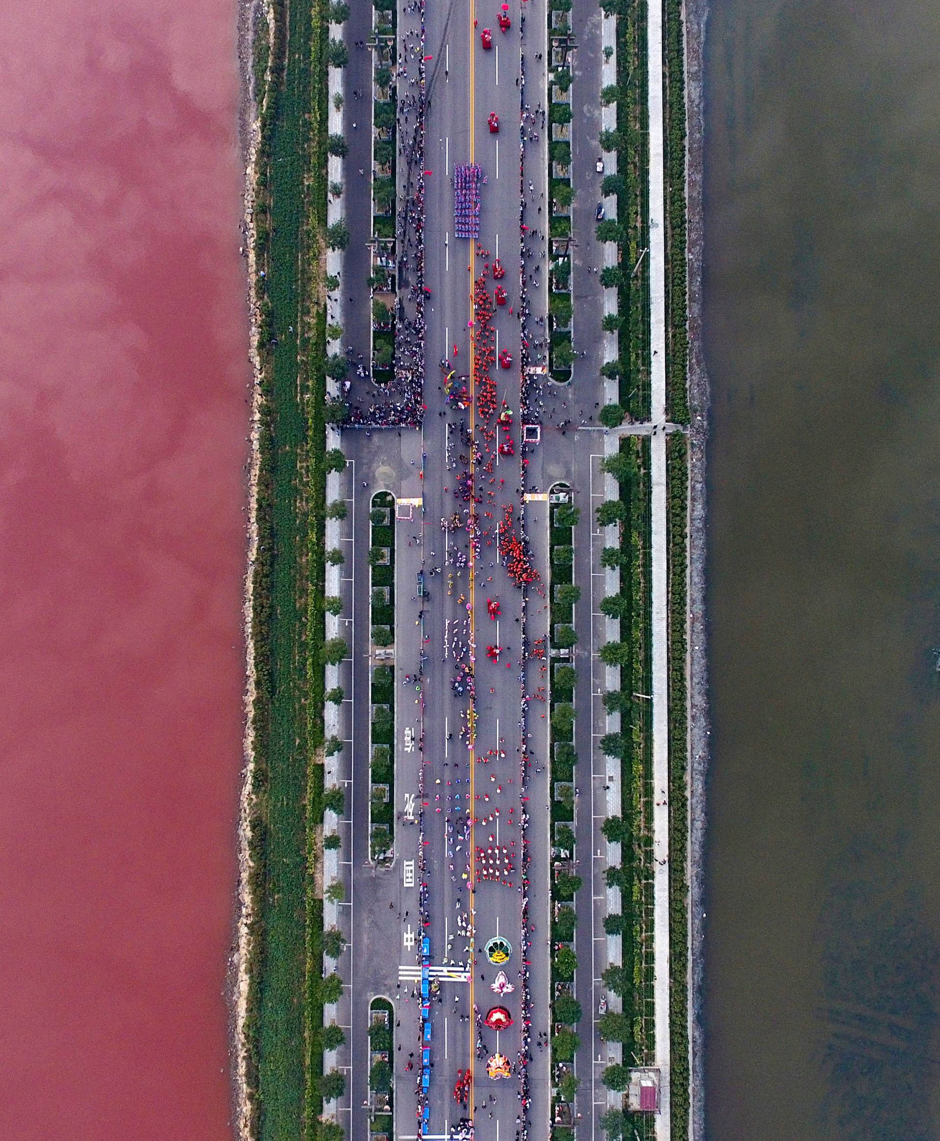 A salt lake which is separated by a road, shows parts of it in different colours due to algae, in Yuncheng, Shanxi Province, China