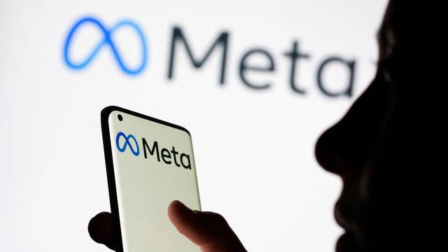 FILE PHOTO: Woman holds smartphone with Meta logo in front of a displayed Facebook's new rebrand logo Meta in this illustration picture