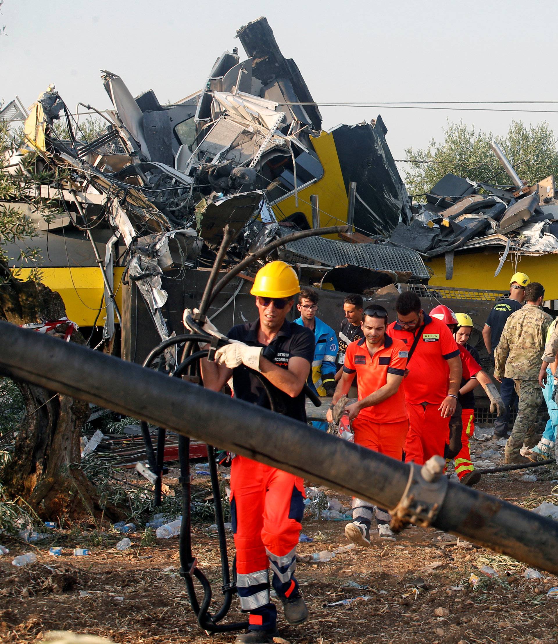Rescuers work at the site where two passenger trains collided in the middle of an olive grove in the southern village of Corato
