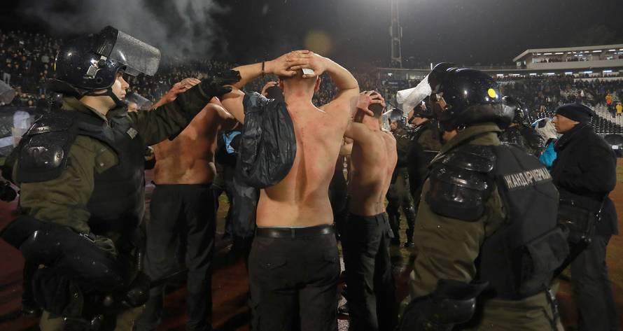 Police escort the soccer fans injured during the fights at a match between Red Star and Partizan in Belgrade