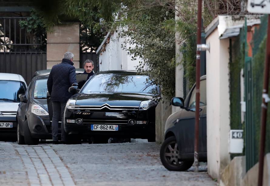 Former French President Nicolas Sarkozy enters his car as he leaves his house in Paris
