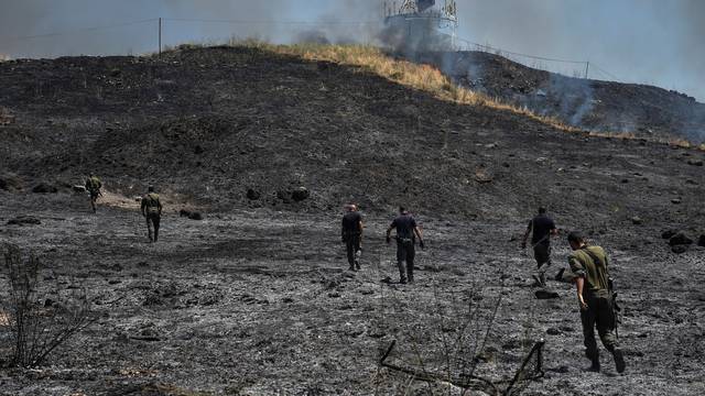 Israeli security forces inspect the area where fire broke out following a landing of a rocket that was fired at Israel from Lebanon, in Kiryat Shmona