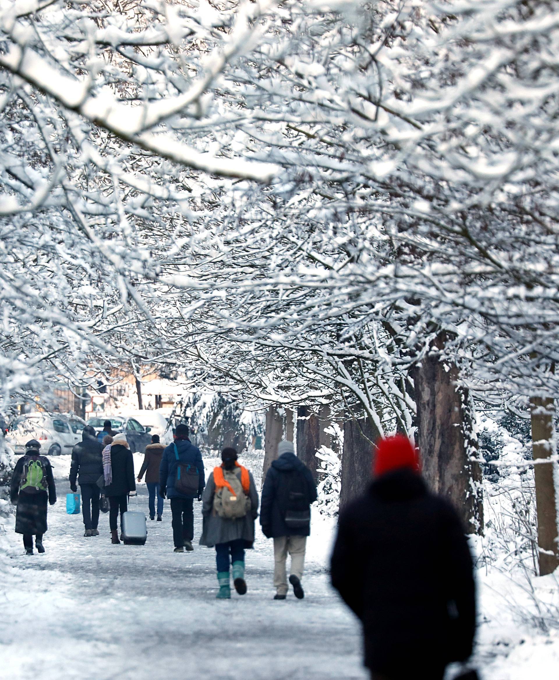 People walk on a snow-covered path in the Bois de Vincennes in Paris as winter weather with snow and freezing temperatures arrive in France