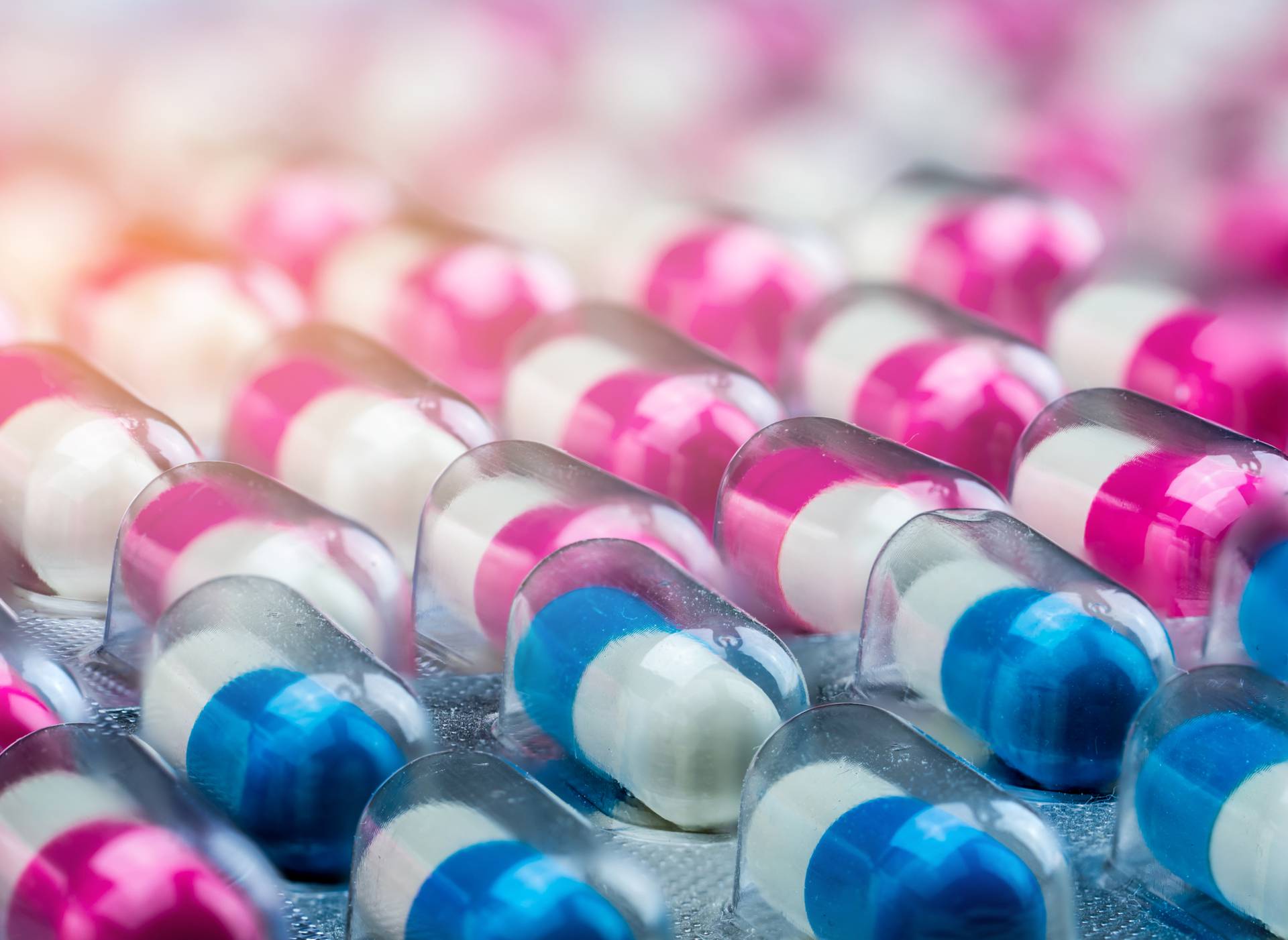 Closeup pink-white and blue-white antibiotics capsule pills in b