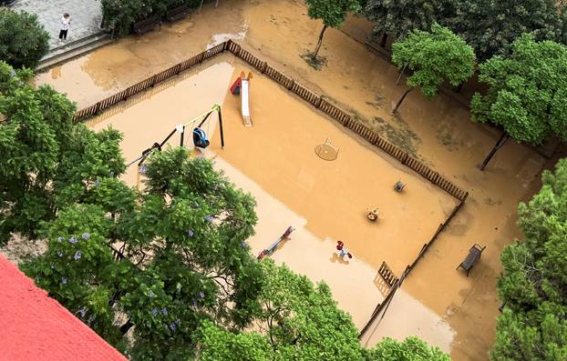 A woman takes a picture of a flooded playground following heavy rain in Sant Adria de Besos on the outskirts of Barcelona