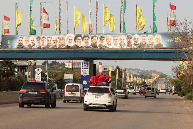 Vehicles drive past a hoarding depicting former Hezbollah leader Hassan Nasrallah and others, after a 10-day ceasefire between Lebanon and Israel went into effect, near Sidon