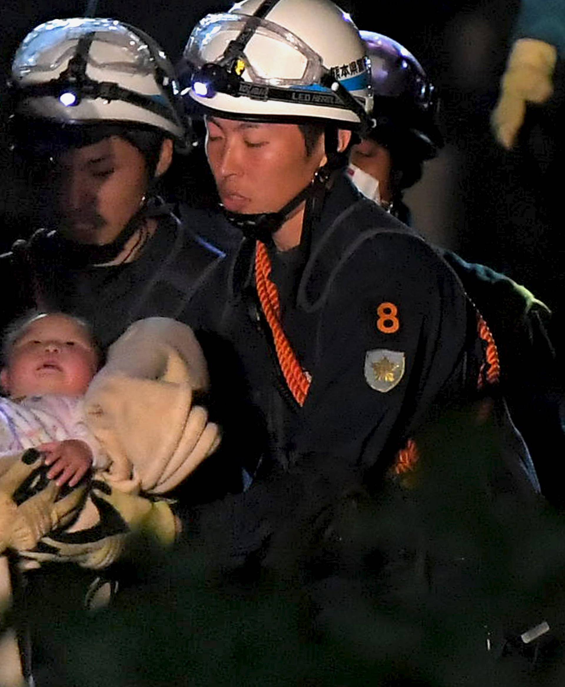 Baby is carried away by rescue workers after being rescued from her collapsed home caused by an earthquake in Mashiki town, Kumamoto prefecture, Japan