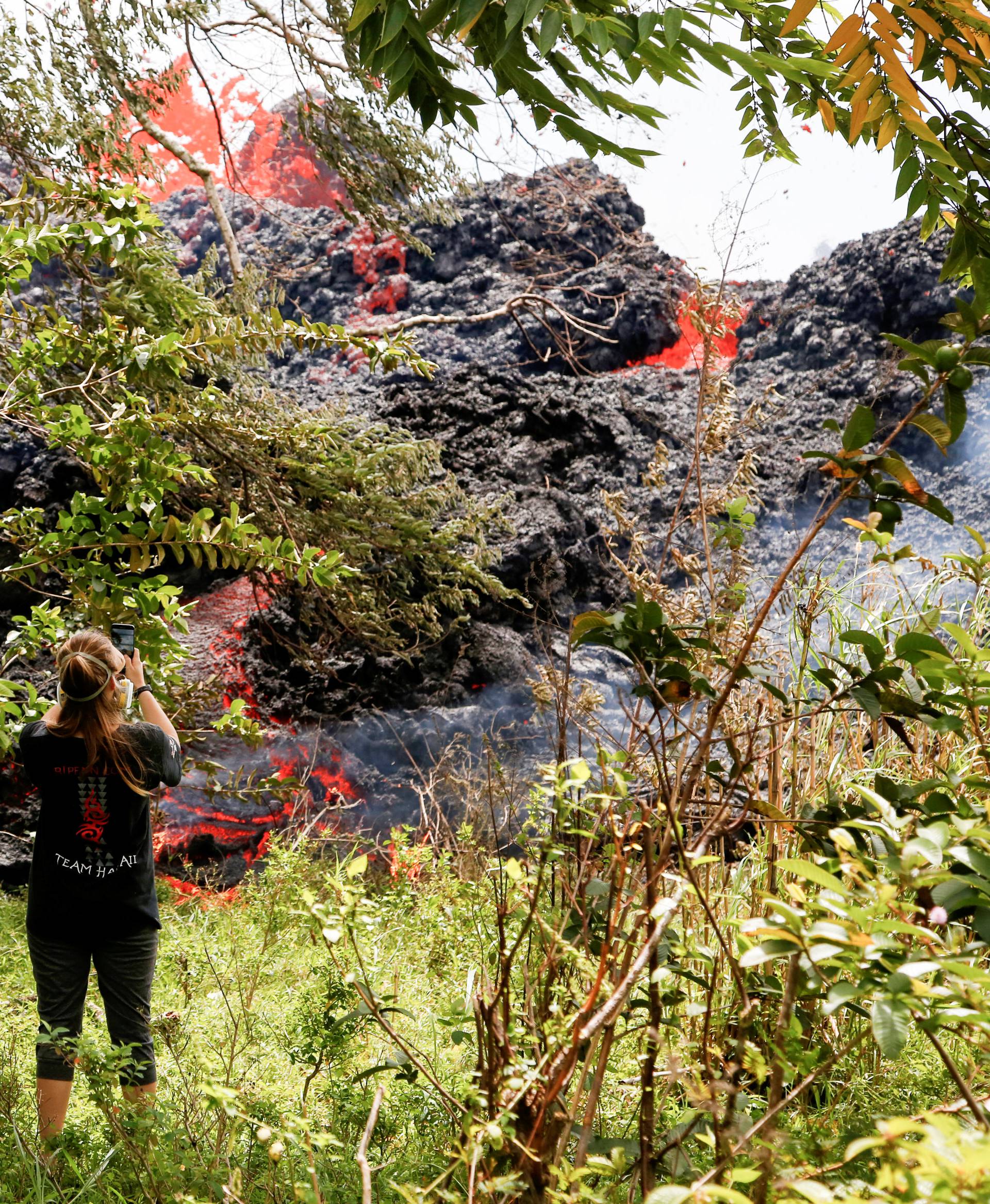 Jolon Clinton, 15, takes photos as lava erupts from a fissure near her home east of the Leilani Estates subdivision during ongoing eruptions of the Kilauea Volcano in Hawaii
