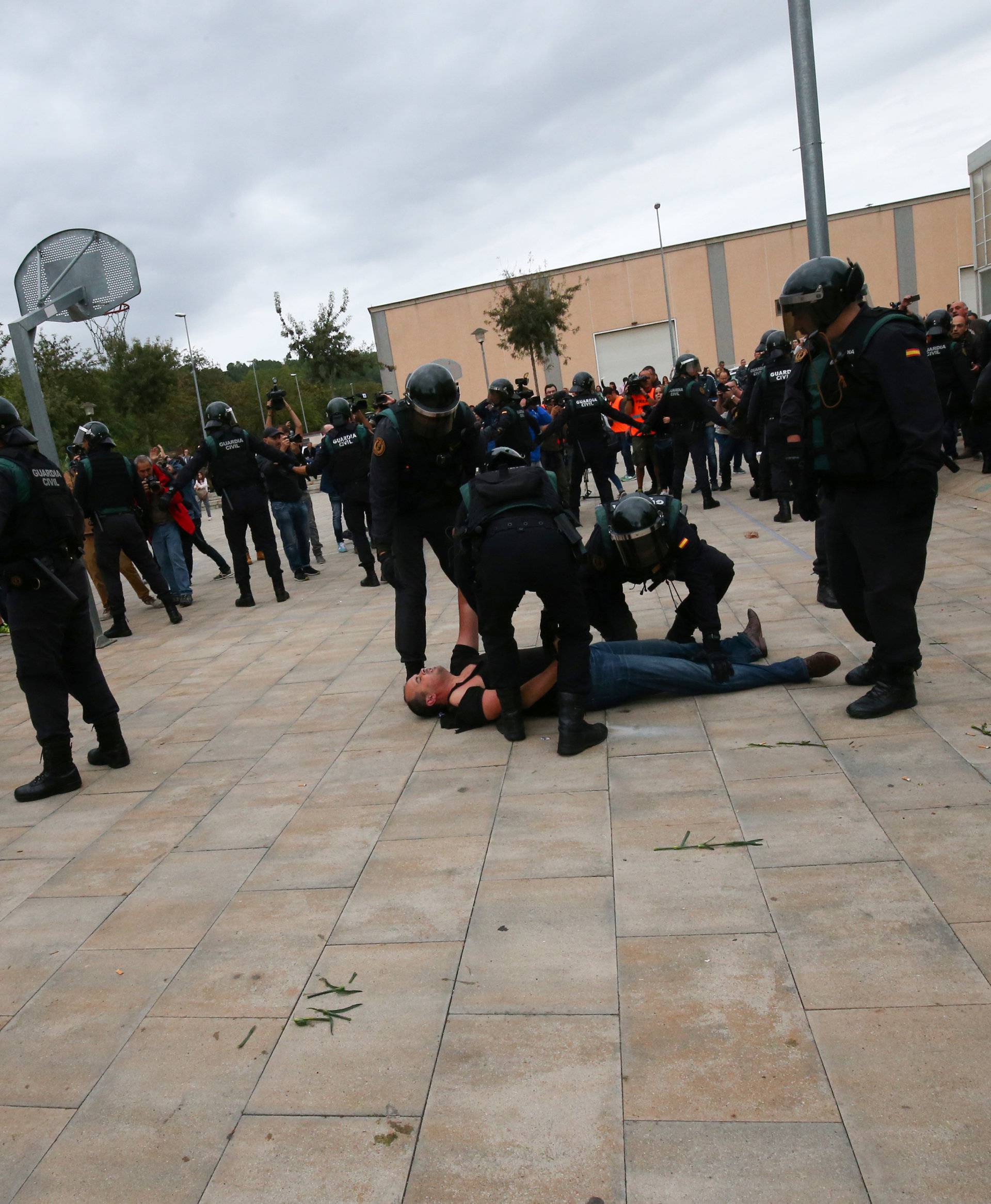 Spanish Civil Guard officers remove a man outside a polling station for the banned independence referendum in Sant Julia de Ramis