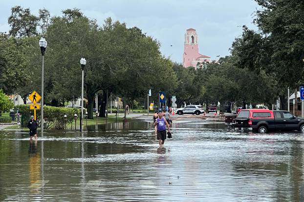 People wade through flood waters after Hurricane Idalia passed to the north, in St. Petersburg
