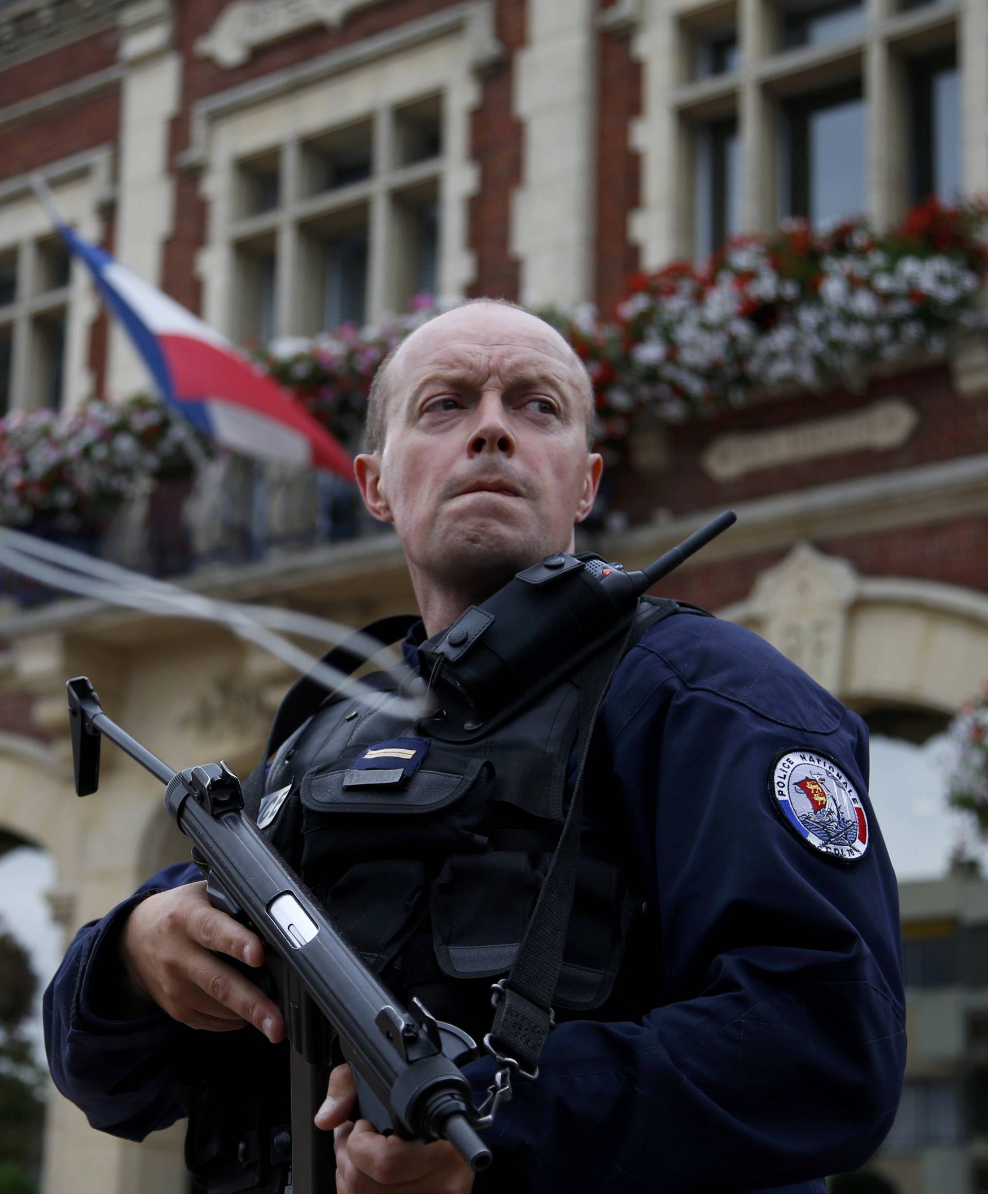 A policeman secures the position in front of the city hall after two assailants had taken five people hostage in the church at Saint-Etienne-du -Rouvray near Rouen in Normandy
