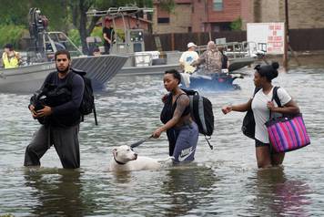 People walk through water to a staging area to evacuate from flood waters from Hurricane Harvey in Dickinson