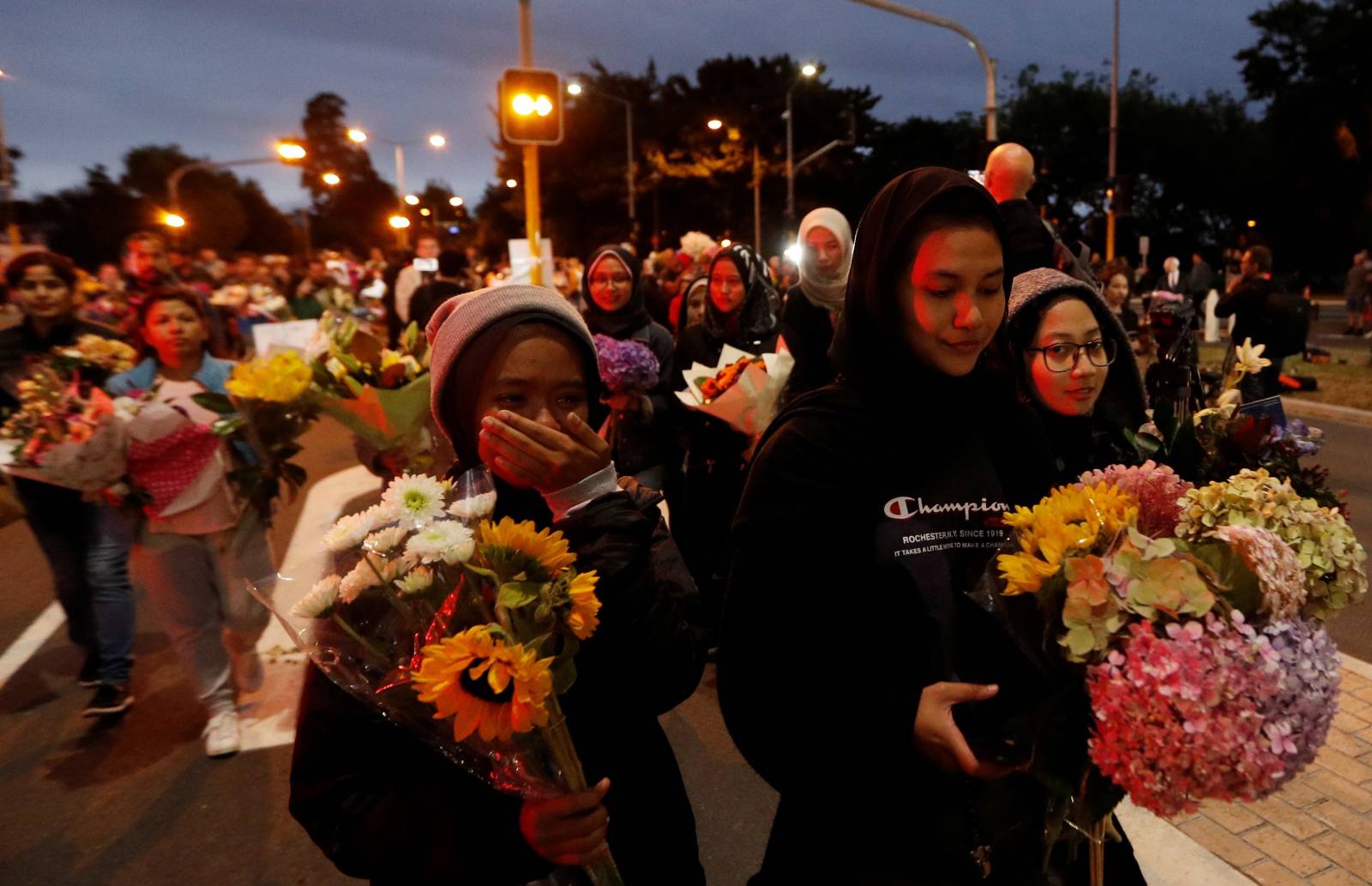 People reacts as they move the flowers after police removed a police line, outside Masjid Al Noor in Christchurch