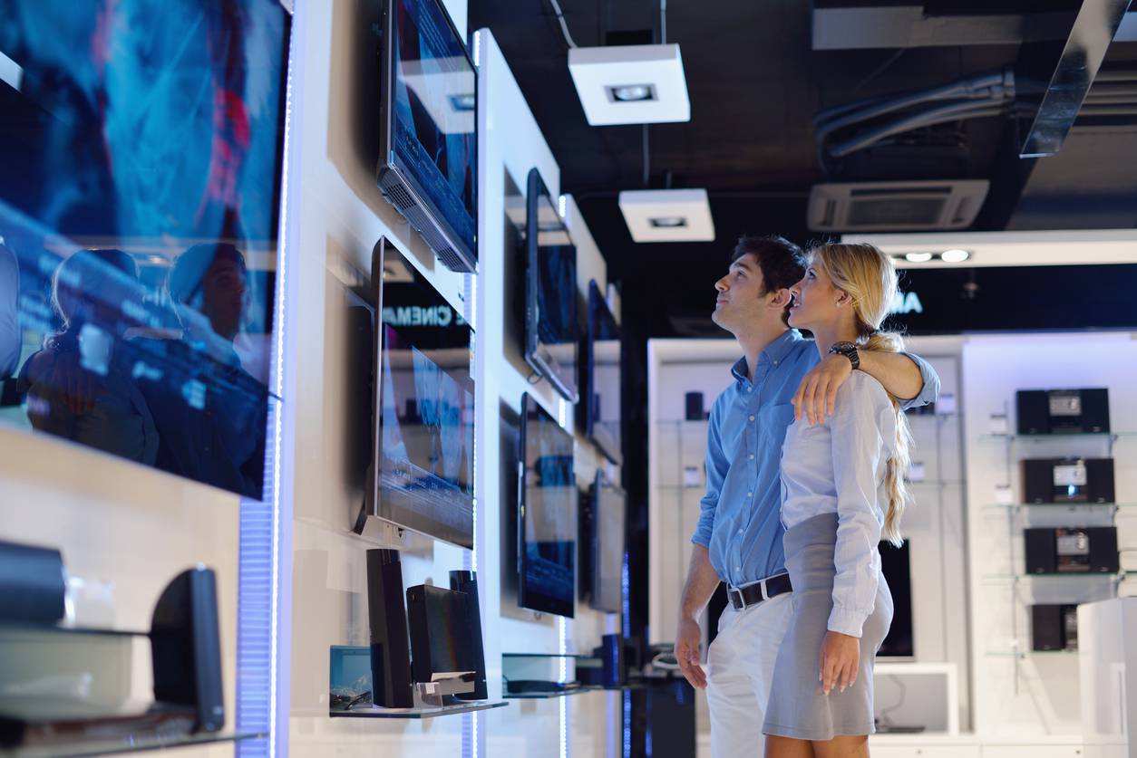 Young couple in consumer electronics store buy tv