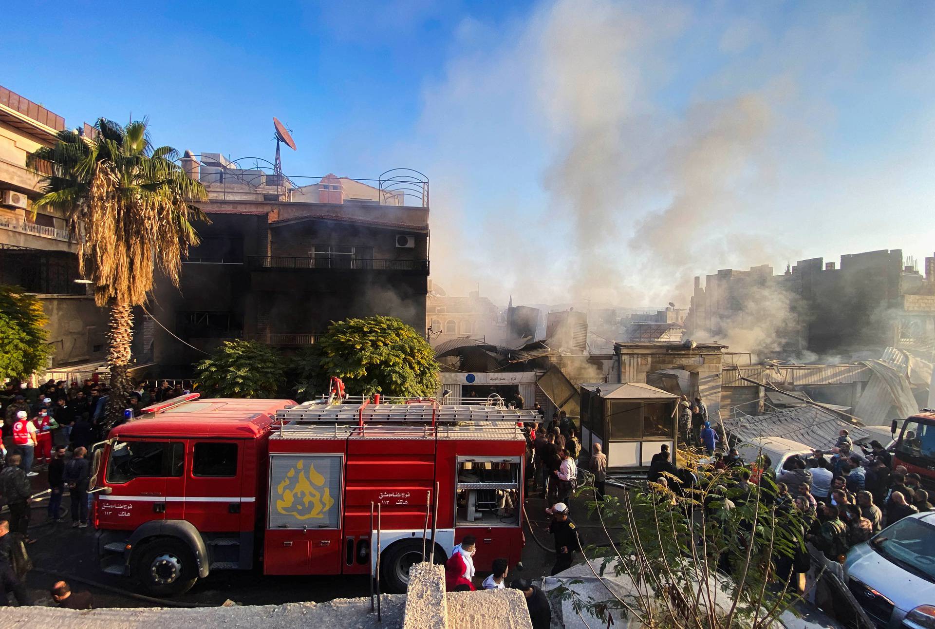 Smoke rises as people gather at a damaged site after what Syrian state news agency said was an Israeli strike in Damascus suburb of Mazzeh