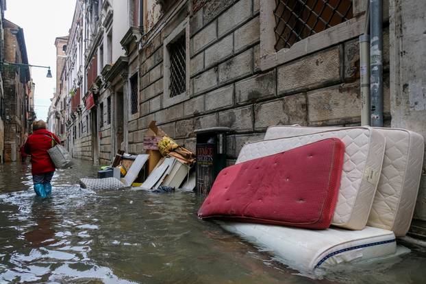 A woman walks in the flooded street during a period of seasonal high water in Venice