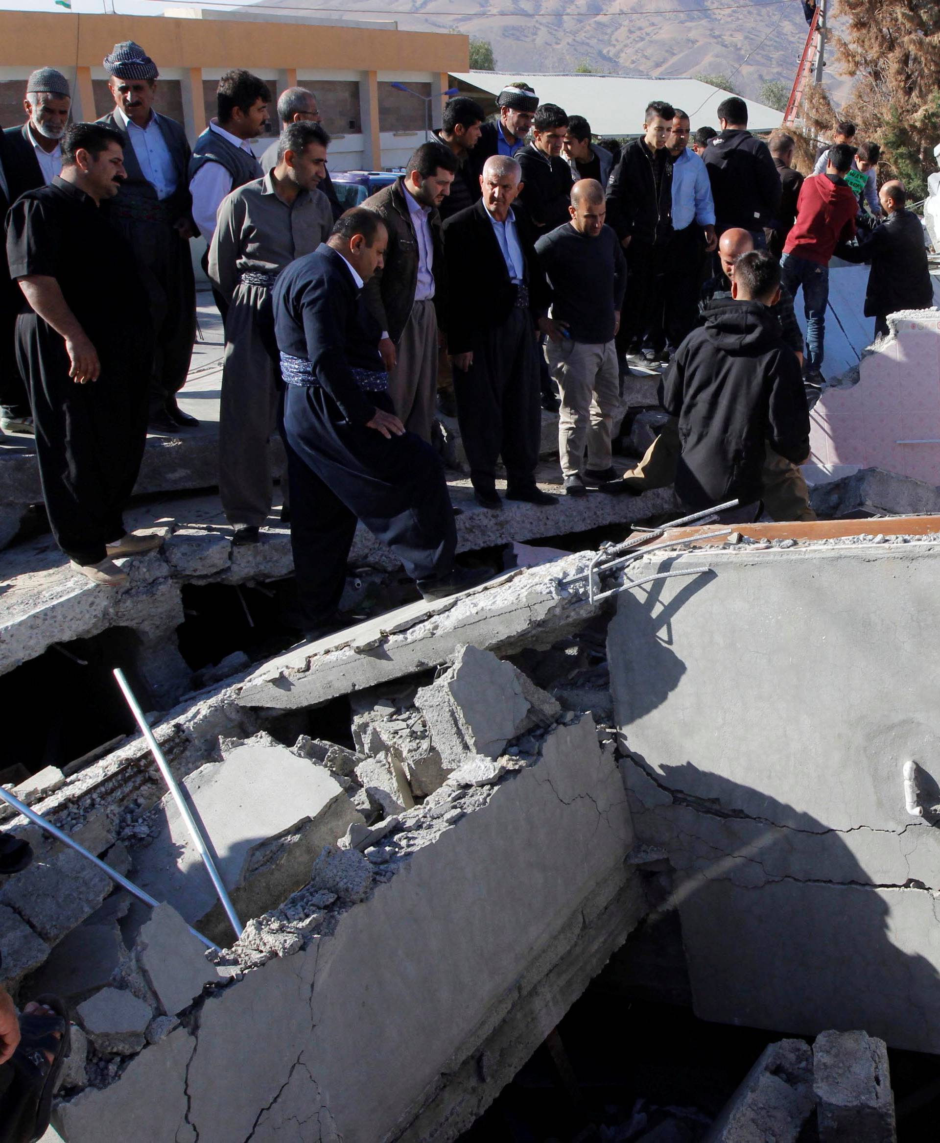 Residents gather near a damaged building following an earthquake in the town of Darbandikhan