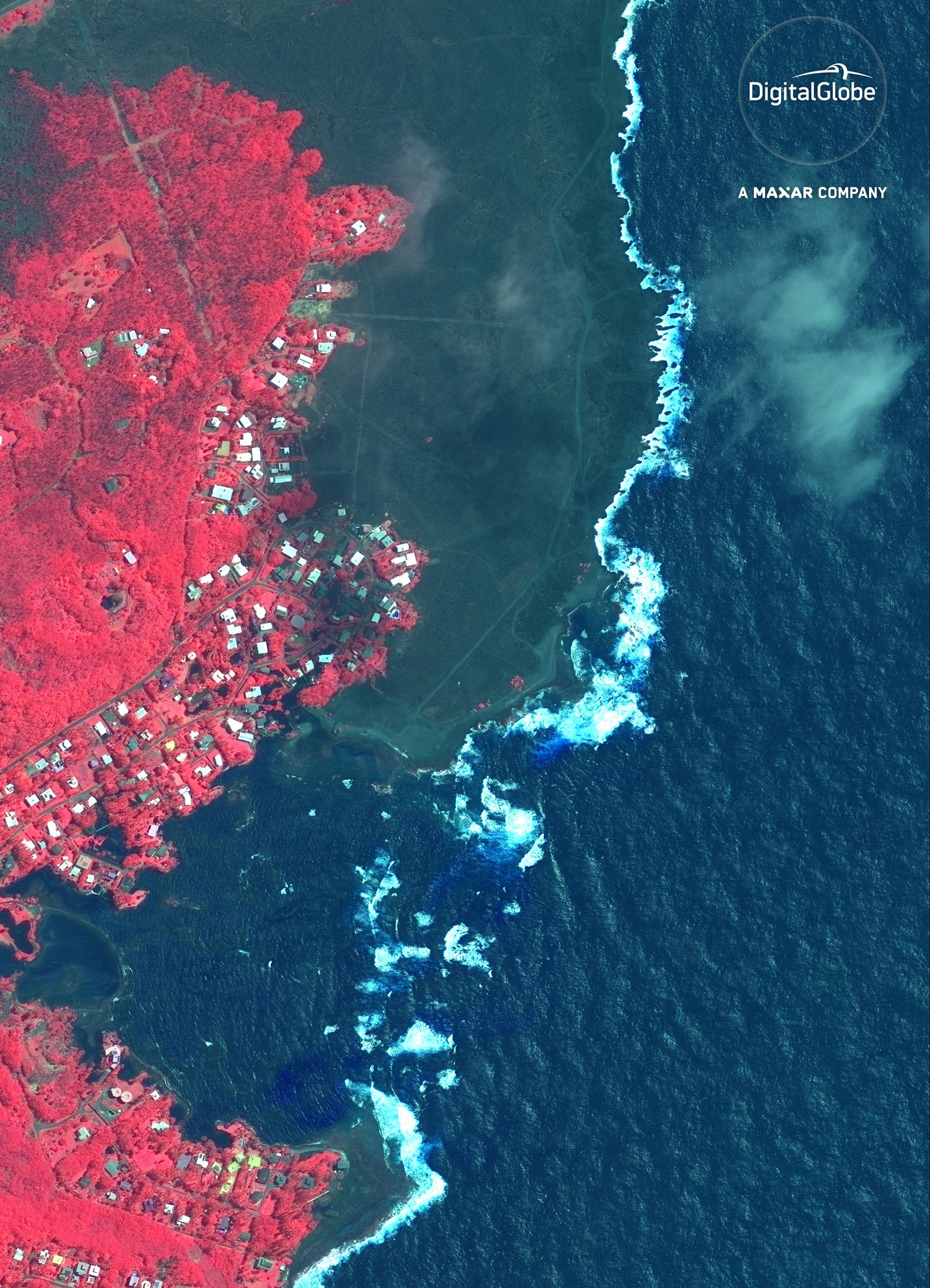 A color infrared satellite image shows lava from the Kilauea volcano eruption encroaching a residential area in Kapoho Bay
