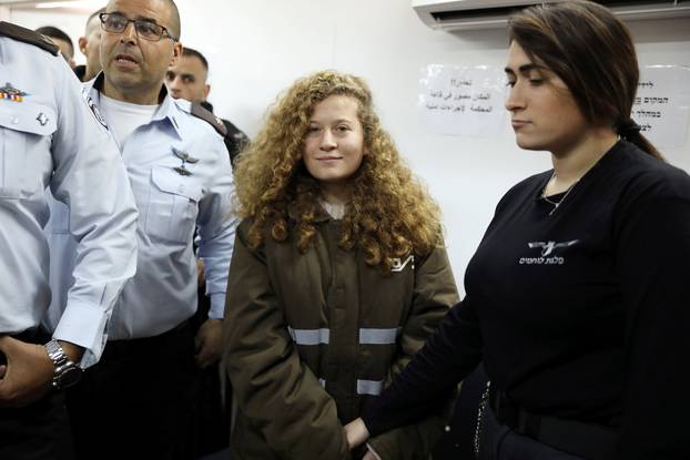 Palestinian teen Ahed Tamimi enters a military courtroom escorted by Israeli security personnel at Ofer Prison, near the West Bank city of Ramallah