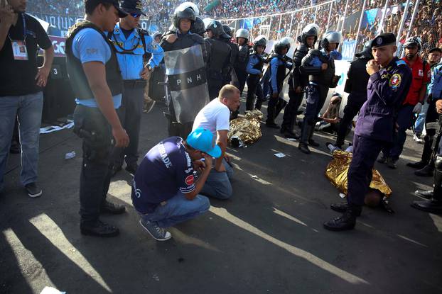 Men react next to two dead bodies after an stampede at the National Stadium in Tegucigalpa, Honduras