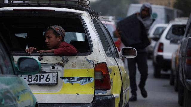 An Afghan boy sits at the back of a car on a street in Kabul