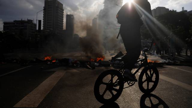 A demonstrator rides his bicycle near a fire barricade  during a rally in Caracas, Venezuela