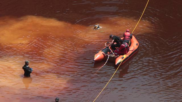 Police forensics officers, rescuers and divers retrieve a suitcase near the village of Mitsero