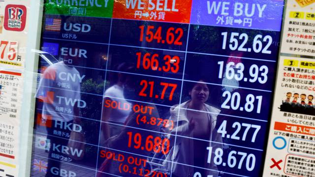 FILE PHOTO: People are reflected on an electric screen displaying Japanese Yen exchange rates against the U.S. dollar and other foreign currencies at a currency exchange shop in Tokyo