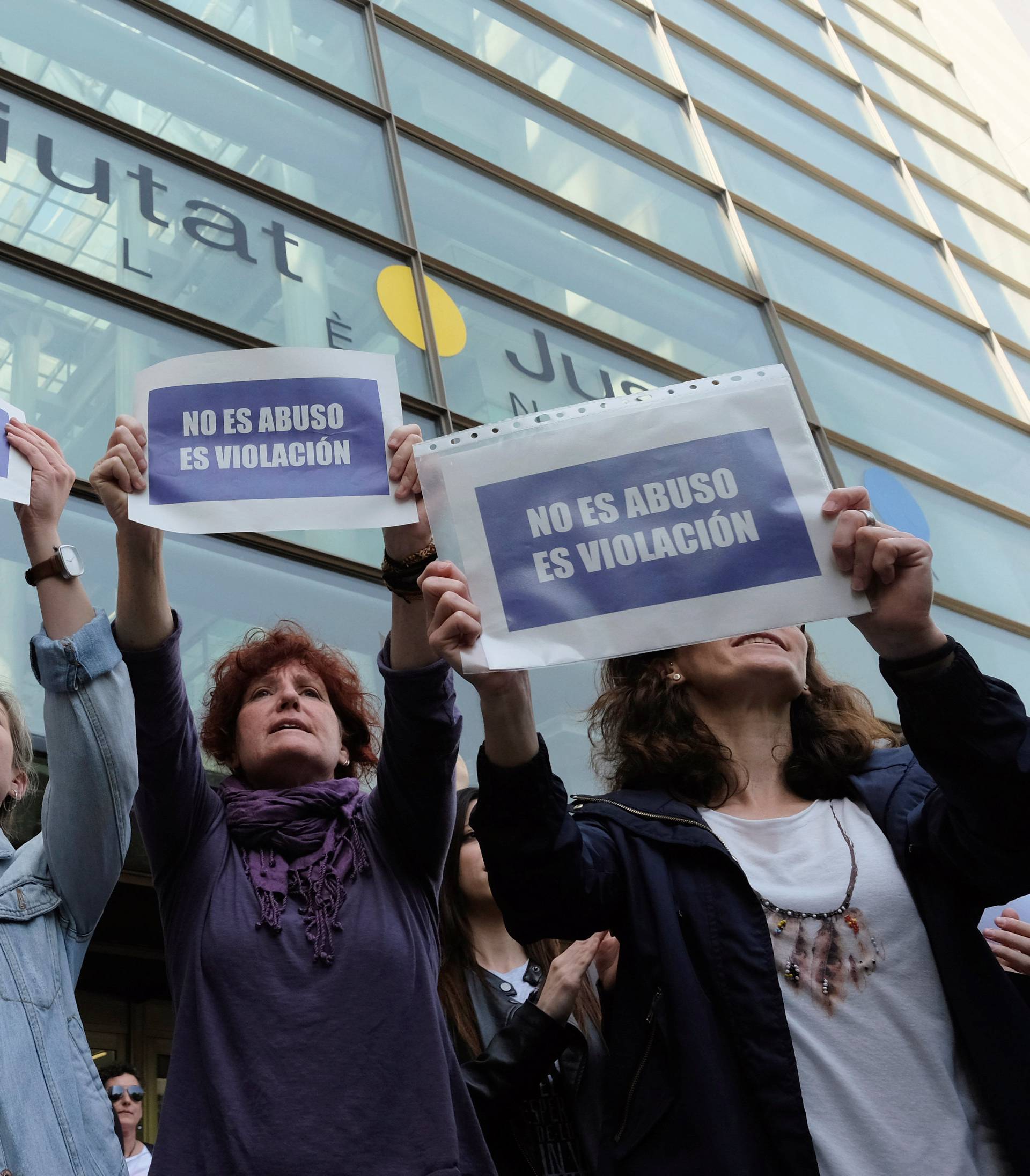 People shout slogans while holding signs during a protest outside the City of Justice in Valencia