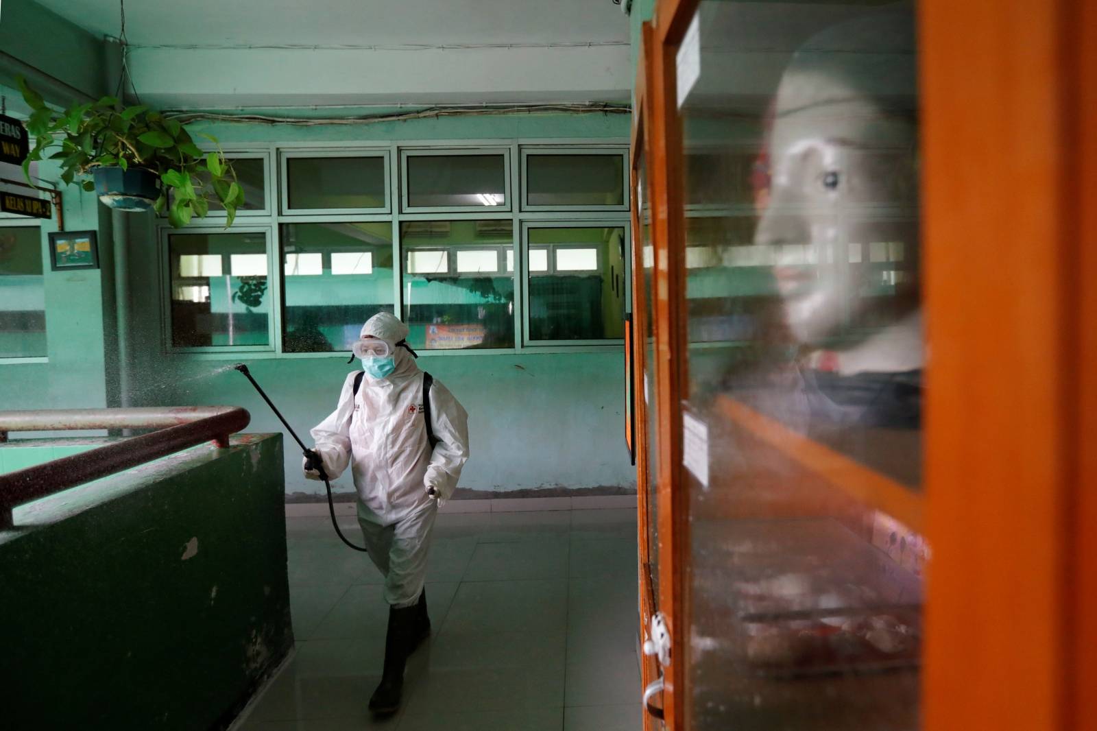 A volunteer from Indonesia's Red Cross sprays disinfectant at the corridor of a school closed amid the spread of coronavirus in Jakarta