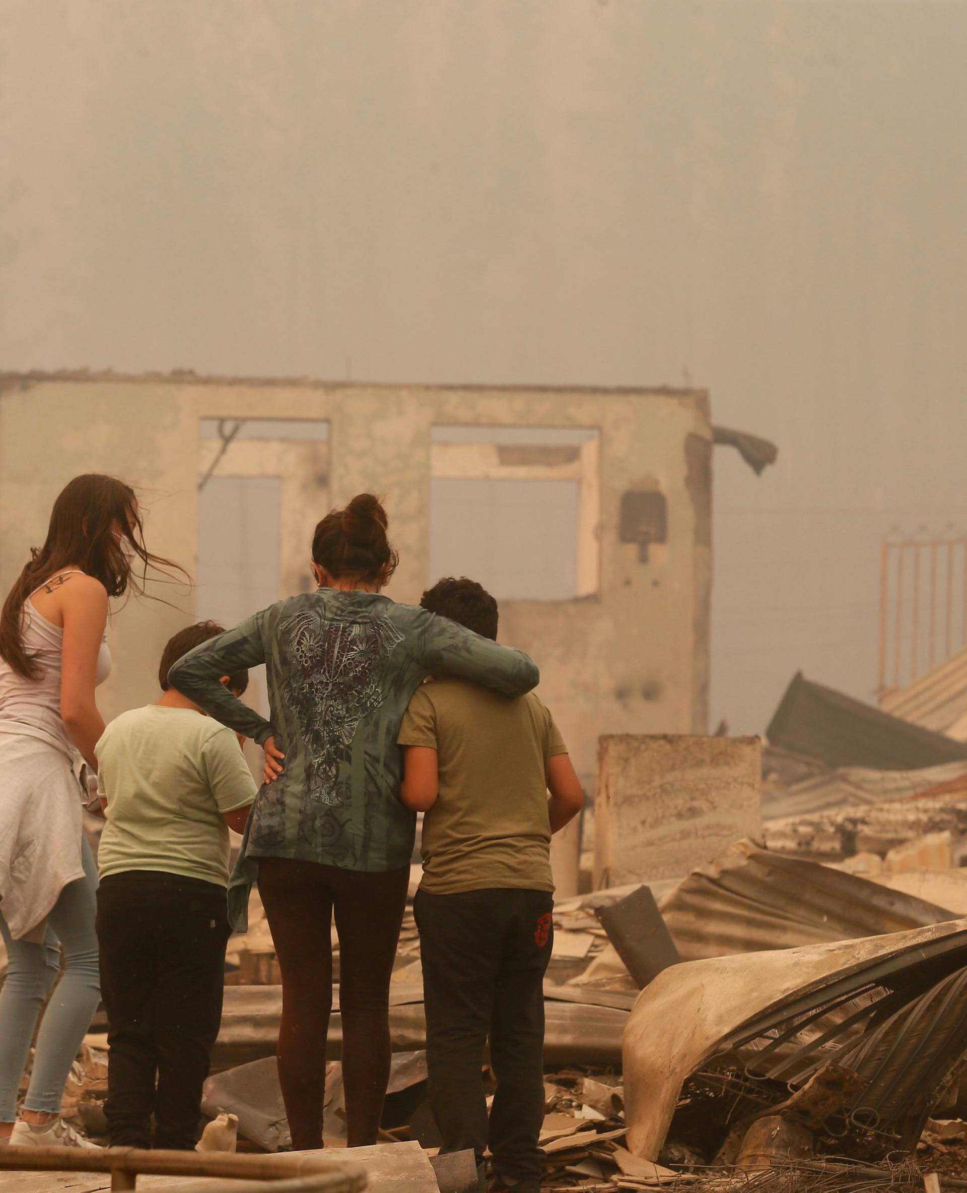 A woman and children look at the remains of a burnt house in Santa Olga