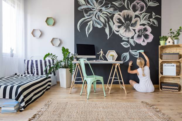 Woman drawing flowers on chalkboard wall in multifunctional home