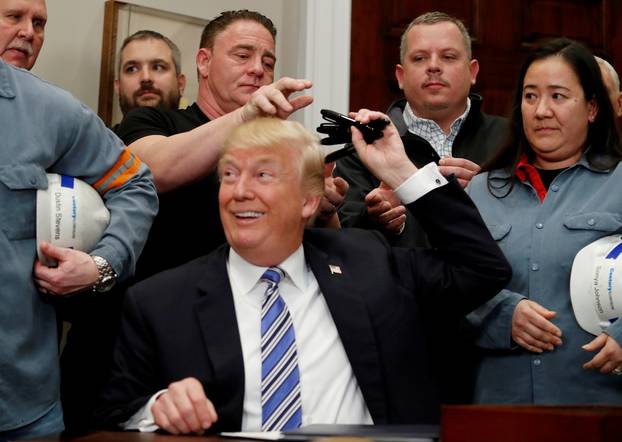 FILE PHOTO: FILE PHOTO: U.S. President Donald Trump signs a presidential proclamation placing tariffs on steel and aluminum imports while surrounded by workers from the steel and aluminum industries at the White House in Washington