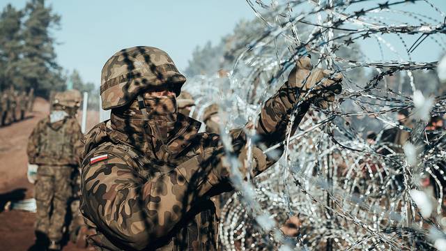 A Polish soldier instals barbed wire on the Poland/Belarus border near Kuznica
