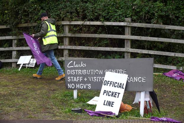 A striking worker walks outside the Clarks distribution centre, in Street, Somerset