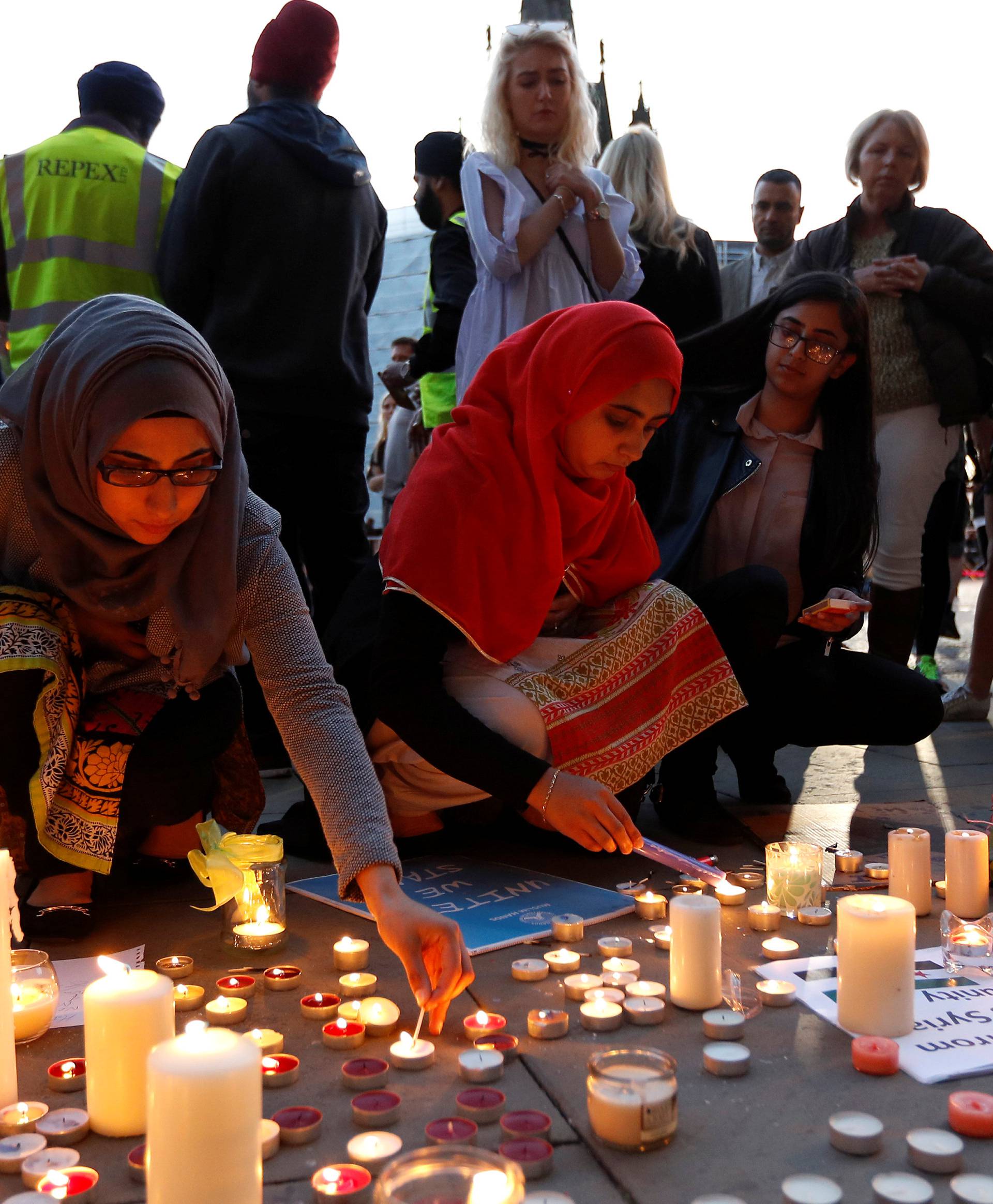 Women light candles following a vigil in central Manchester