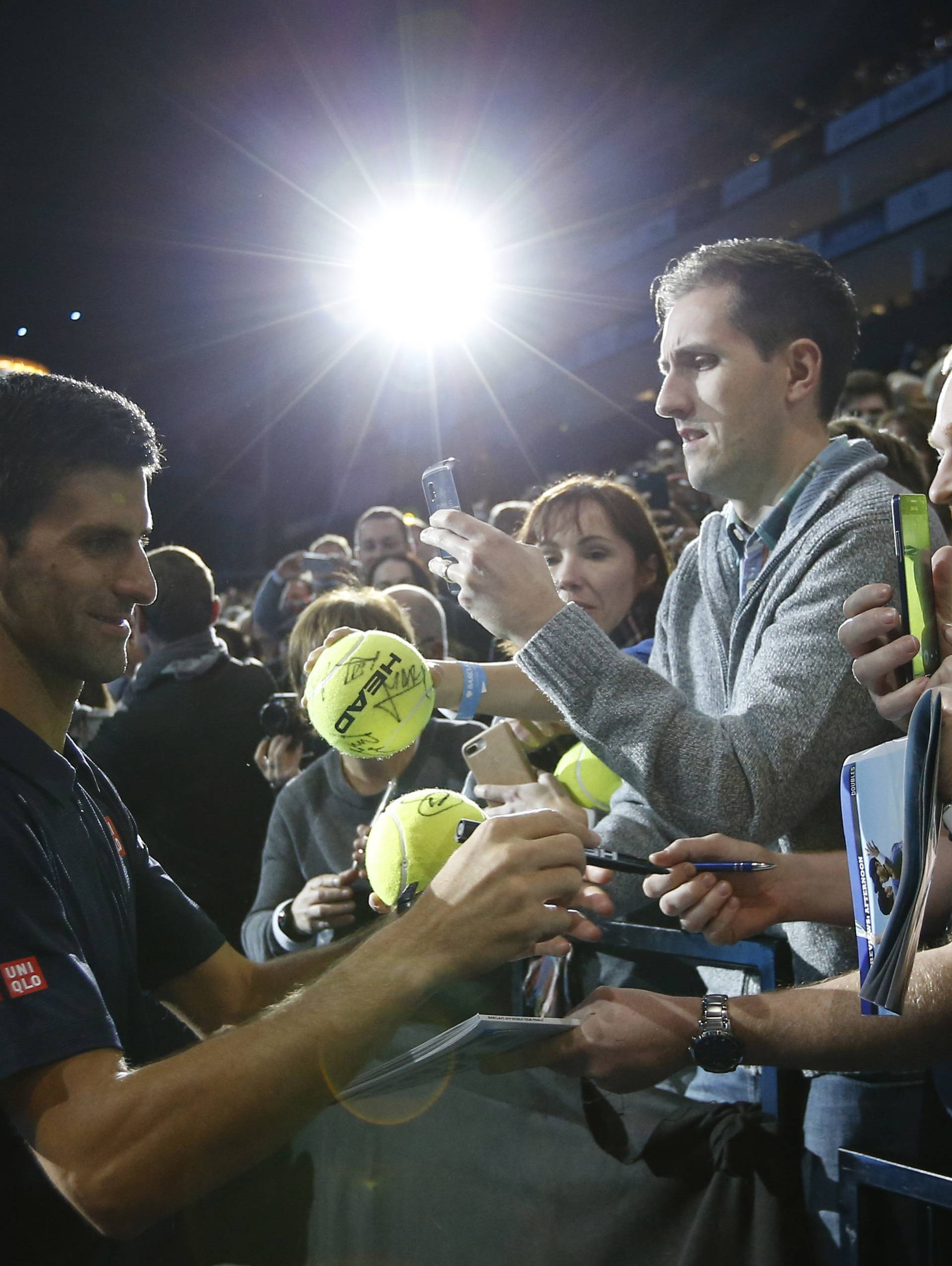 Serbia's Novak Djokovic signs his autograph for spectators after winning his round robin match with Belgium's David Goffin