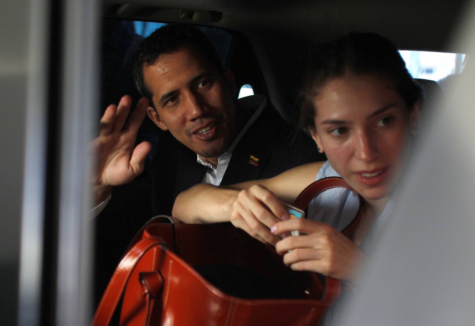 Venezuelan opposition leader Juan Guaido, who many nations have recognized as the country's rightful interim ruler, waves next to his wife Fabiana Rosales while leaving a hotel in Salinas