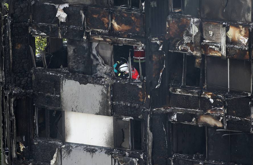 A firefighter examines material in a tower block severely damaged by a serious fire, in north Kensington, West London