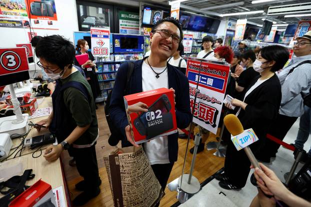 A customers holds his Nintendo Switch 2 game consoles as Nintendo starts selling the new consoles globally, in Tokyo