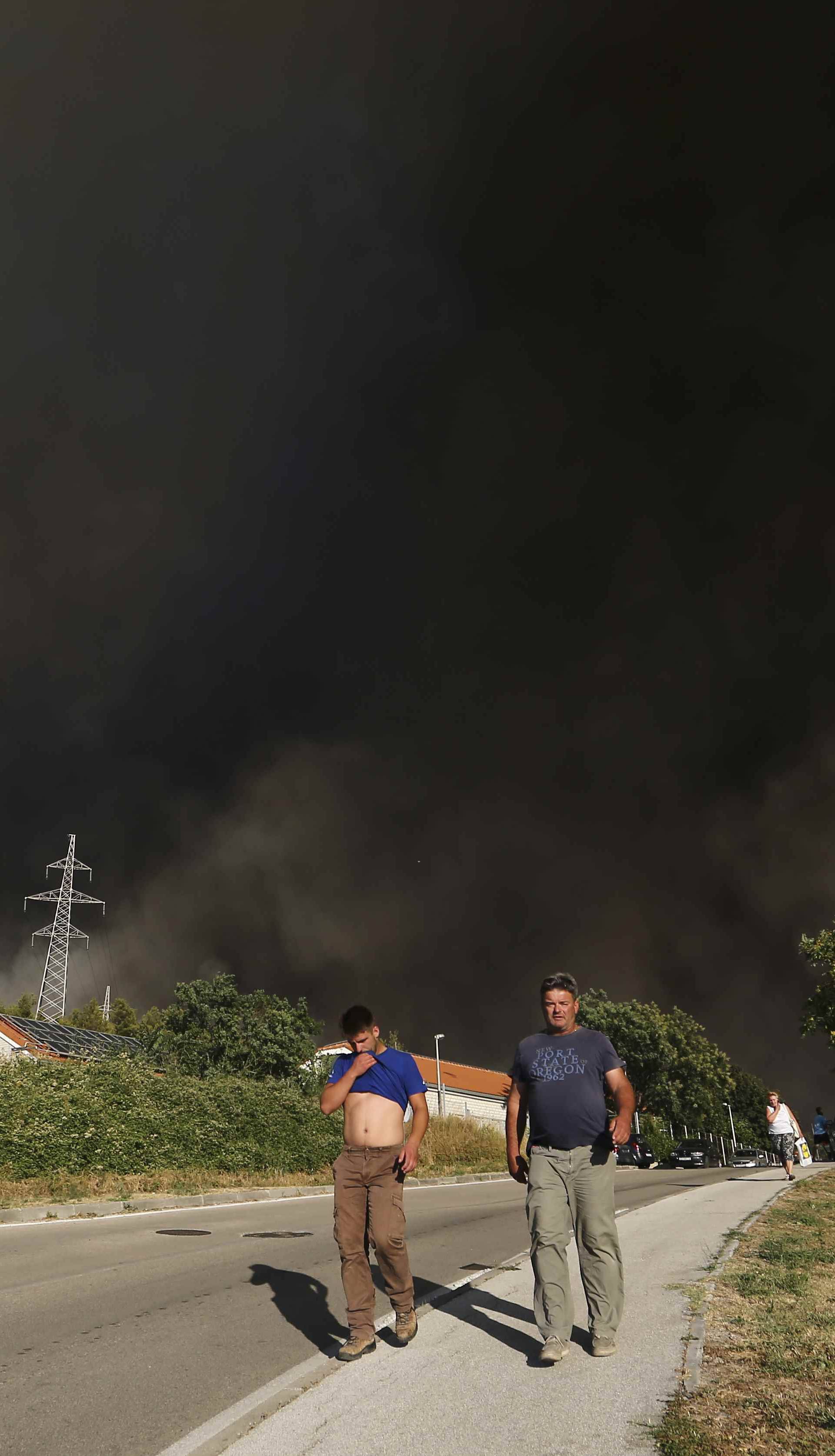 Smoke rises as local residents leave their homes due to a wildfire in the village of Mravinc near Split