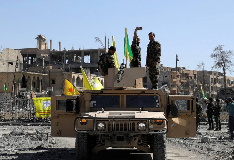 A Fighter of Syrian Democratic Forces takes a selfie as he stands on a military vehicle in Raqqa