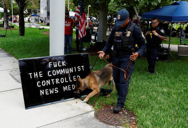 A police dog sniffs a sign after police officers removed the sign from a post near The Wilkie D. Ferguson Jr. United States Courthouse, in Miami