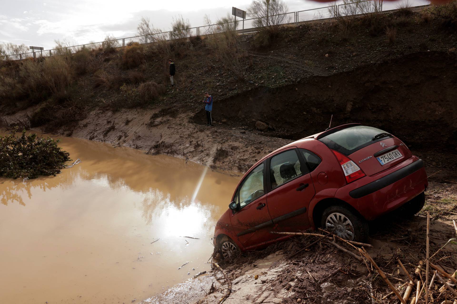 People stand in a flooded area after heavy rains and floods in Alora