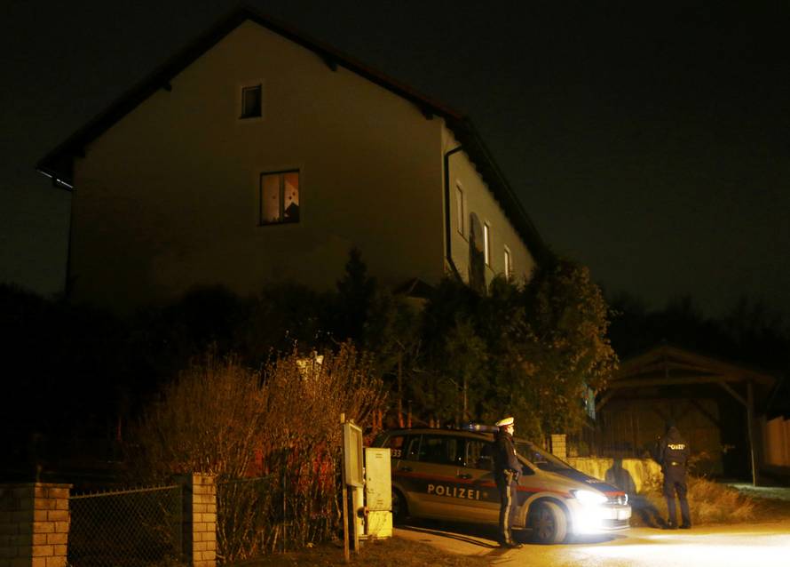Police stand in front of a house where six people were found dead in Boeheimkirchen