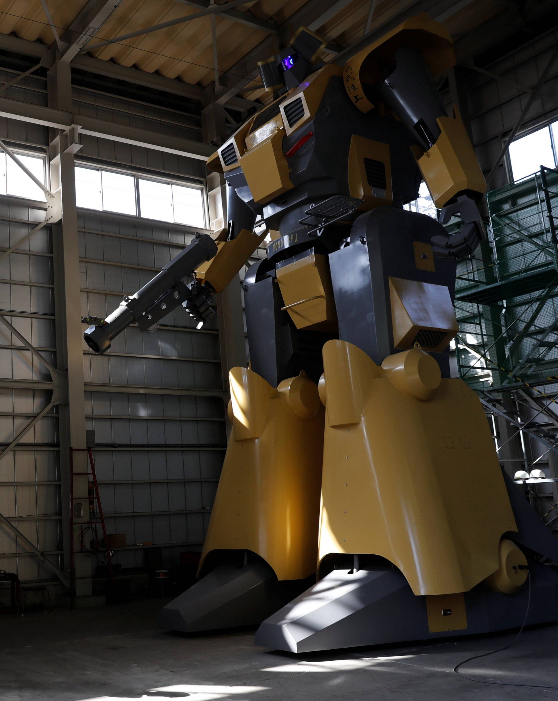 Sakakibara Kikai's engineer Go Sakakibara talks on a mobile phone to communicate with another engineer boarding the bipedal robot Mononofu during its demonstration at its factory in Shinto Village